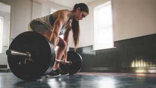 Woman is about to deadlift a barbell
