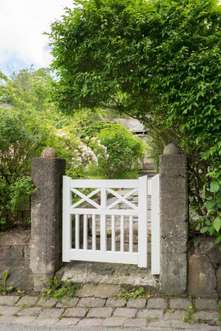 garden gate ideas: white gate between stone posts