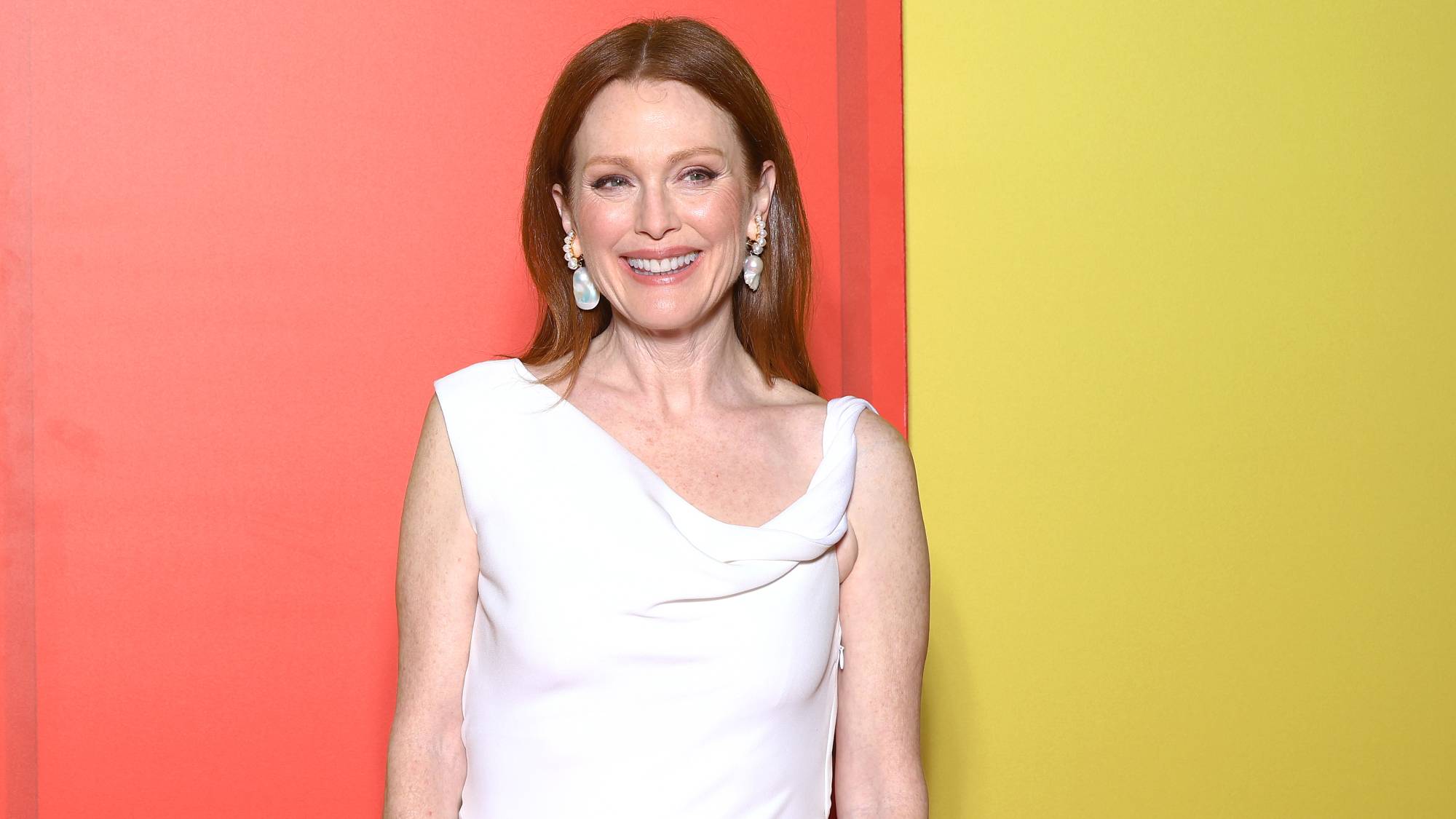 Julianne Moore smiles in front of a pink and yellow wall