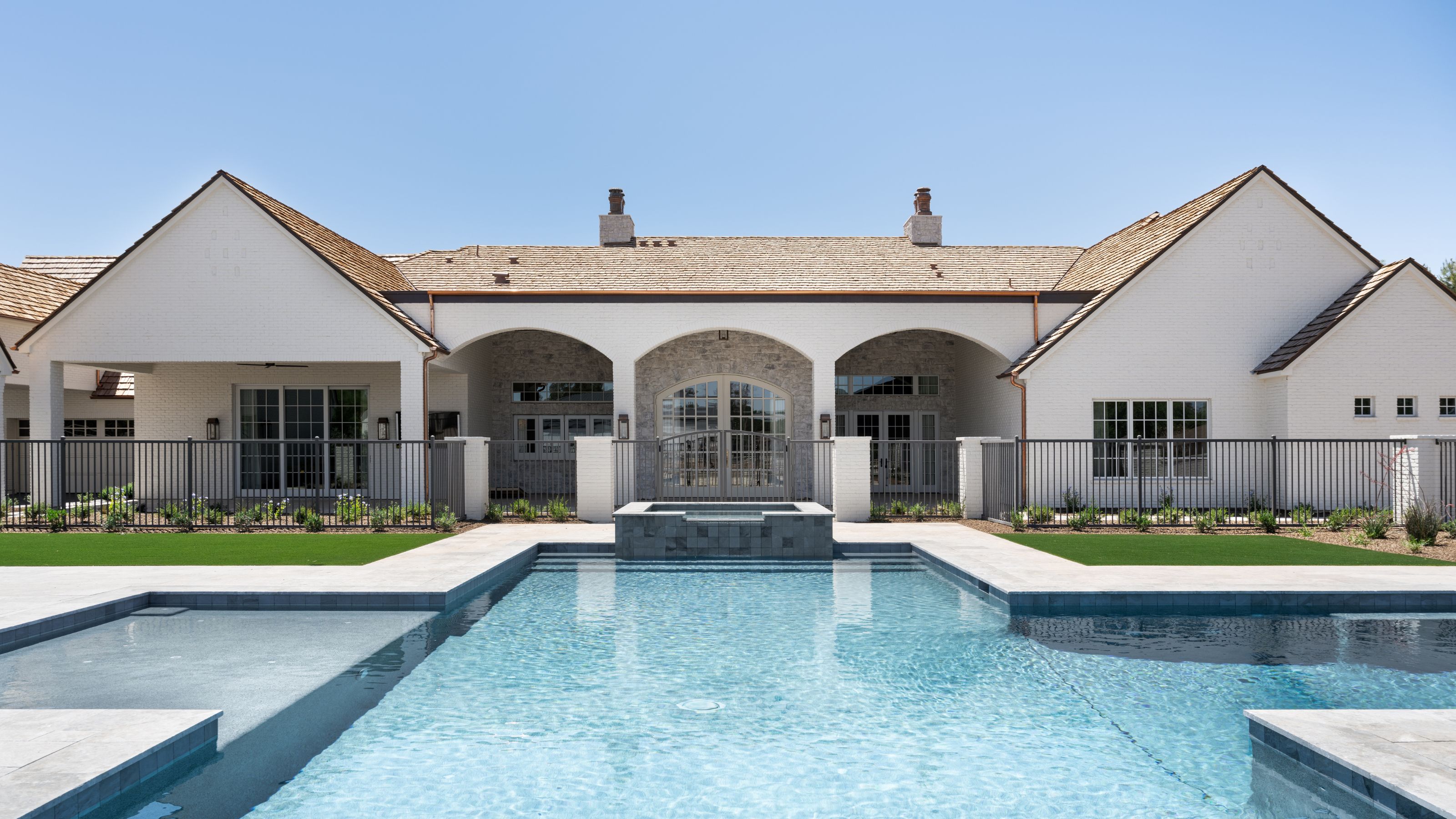 a large home in Arizona with a white faced, arched hangings looking out to a vast pool area
