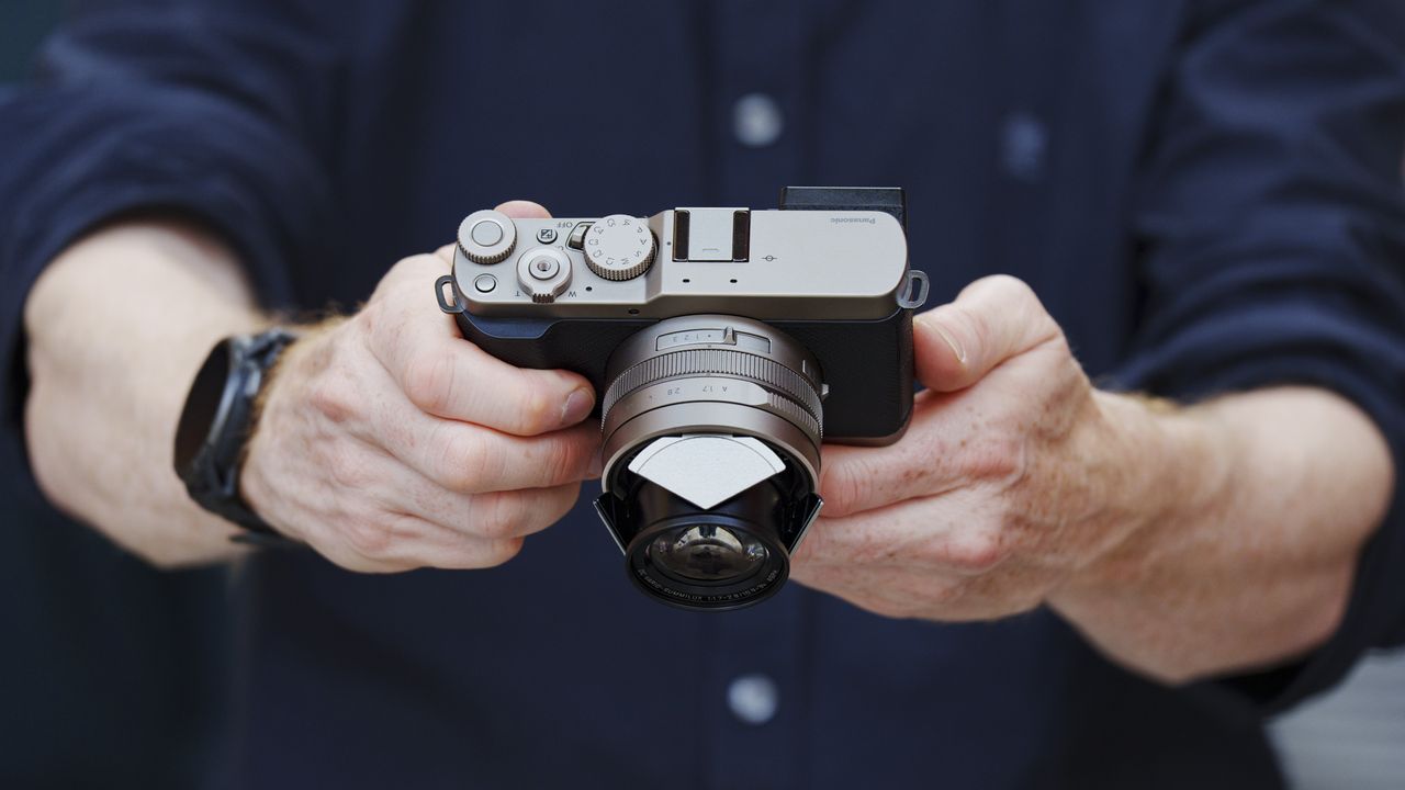 Man holding the Panasonic Lumix L10 compact camera in an urban setting of Japan