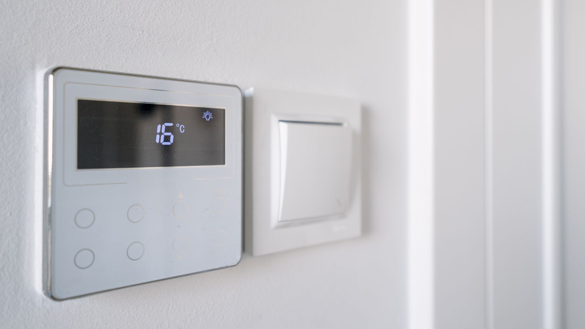 picture of electric thermostat in home next to light switch
