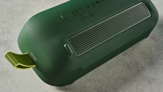 a green bluetooth speaker made by bose with a clean plastic casing and no visible woofers rests on a table