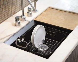simplehuman Black Dishrack in sink with two plates and one glass drying inside, with marble countertops