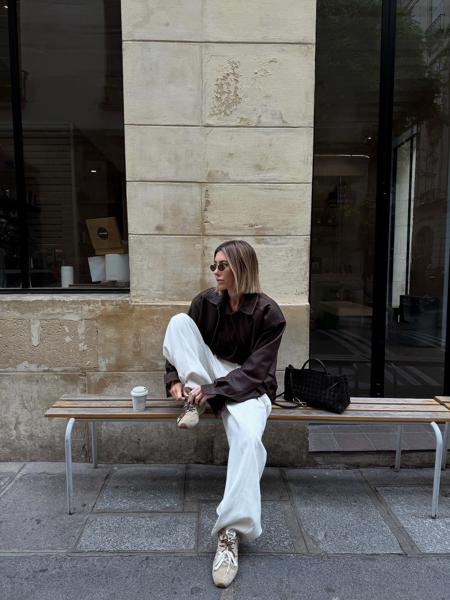 Hannah wears a brown leather jacket, white pants, and beige sneakers—one of the biggest sneaker color trends of 2026.