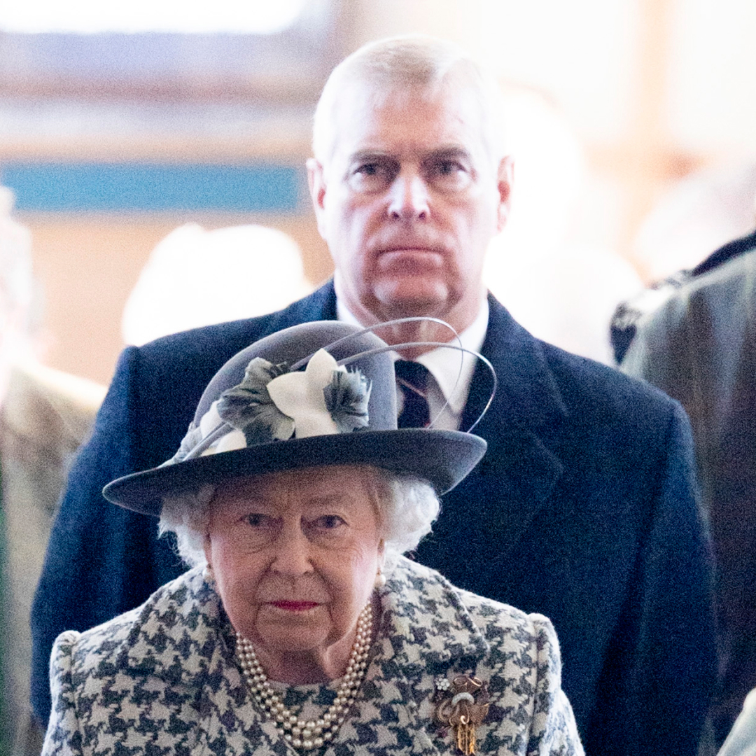Queen Elizabeth wears a white and black jacket and her son ex-Prince Andrew looks stern in the background