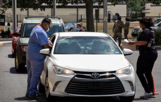 Nurses give shots of the Johnson & Johnson COVID-19 vaccine to people in cars at a drive-thru vaccination site targeted to Asian Americans and Pacific Islanders at Michael McCoy Elementary School.