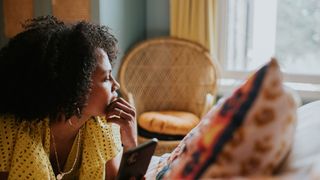 A woman lying down, looking out the window contemplatively