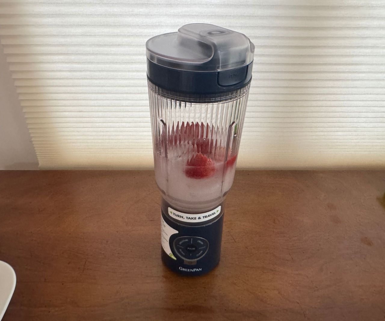 Water and strawberries in a black portable blender.