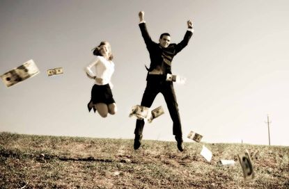 A couple jumps up and down in a field where cash is raining down