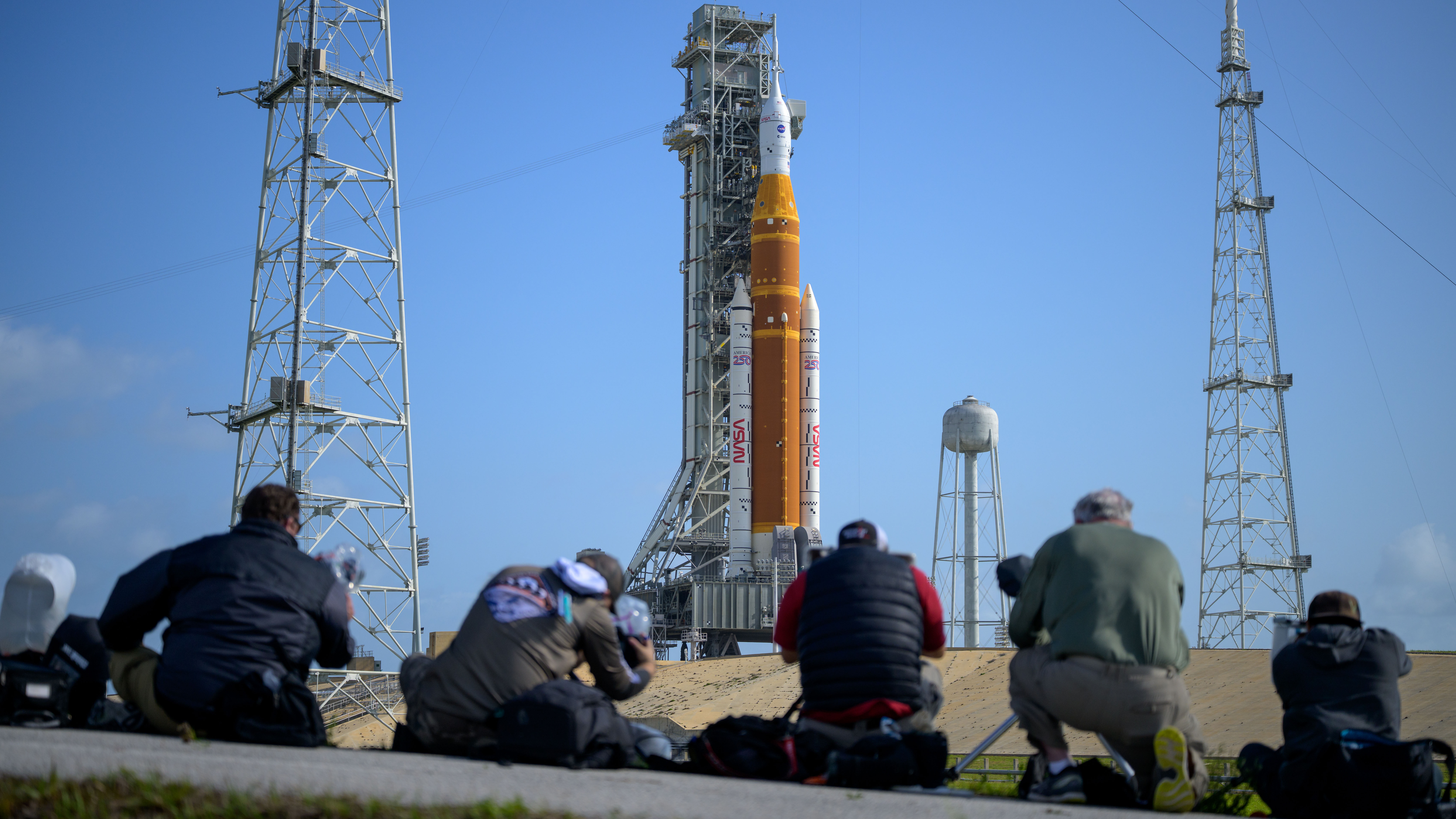 Media aim their remote cameras on NASA&amp;rsquo;s Artemis II Space Launch System (SLS) rocket and Orion spacecraft, atop a mobile launcher at Launch Complex 39B, Sunday, March 29, 2026, at NASA&amp;rsquo;s Kennedy Space Center in Florida. NASA&amp;rsquo;s Artemis II test flight will take Commander Reid Wiseman, Pilot Victor Glover, and Mission Specialist Christina Koch from NASA, and Mission Specialist Jeremy Hansen from the CSA (Canadian Space Agency), around the Moon and back to Earth with launch opportunities beginning in April 2026. Photo Credit: (NASA/Bill Ingalls)