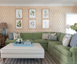 family room with floral patterned wallcovering and green sectional with white leather ottoman