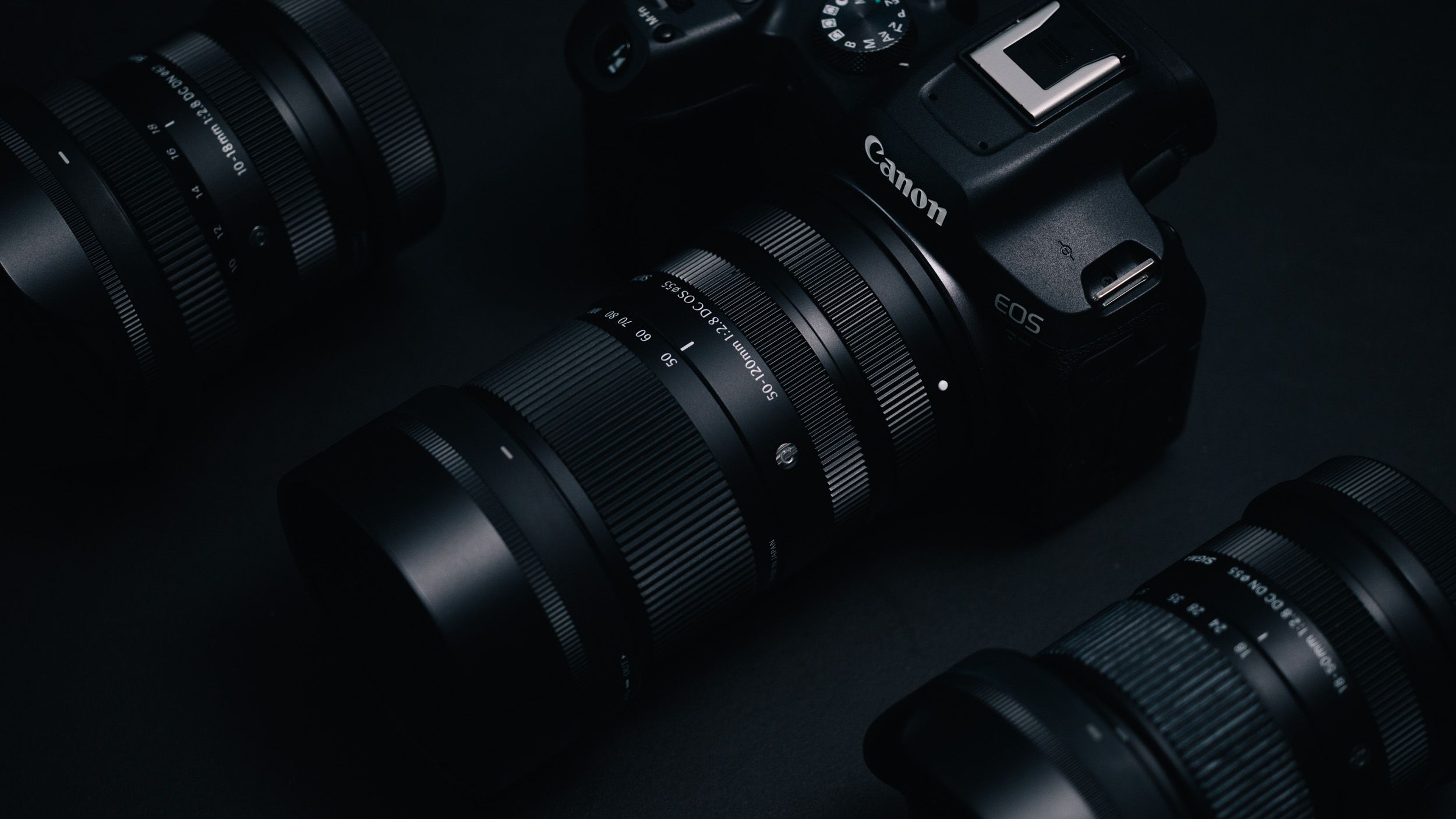 Sigma 50-120mm F2.8 DC OS Contemporary lens attached to a Canon EOS R7, in a lowkey lit studio with dark background
