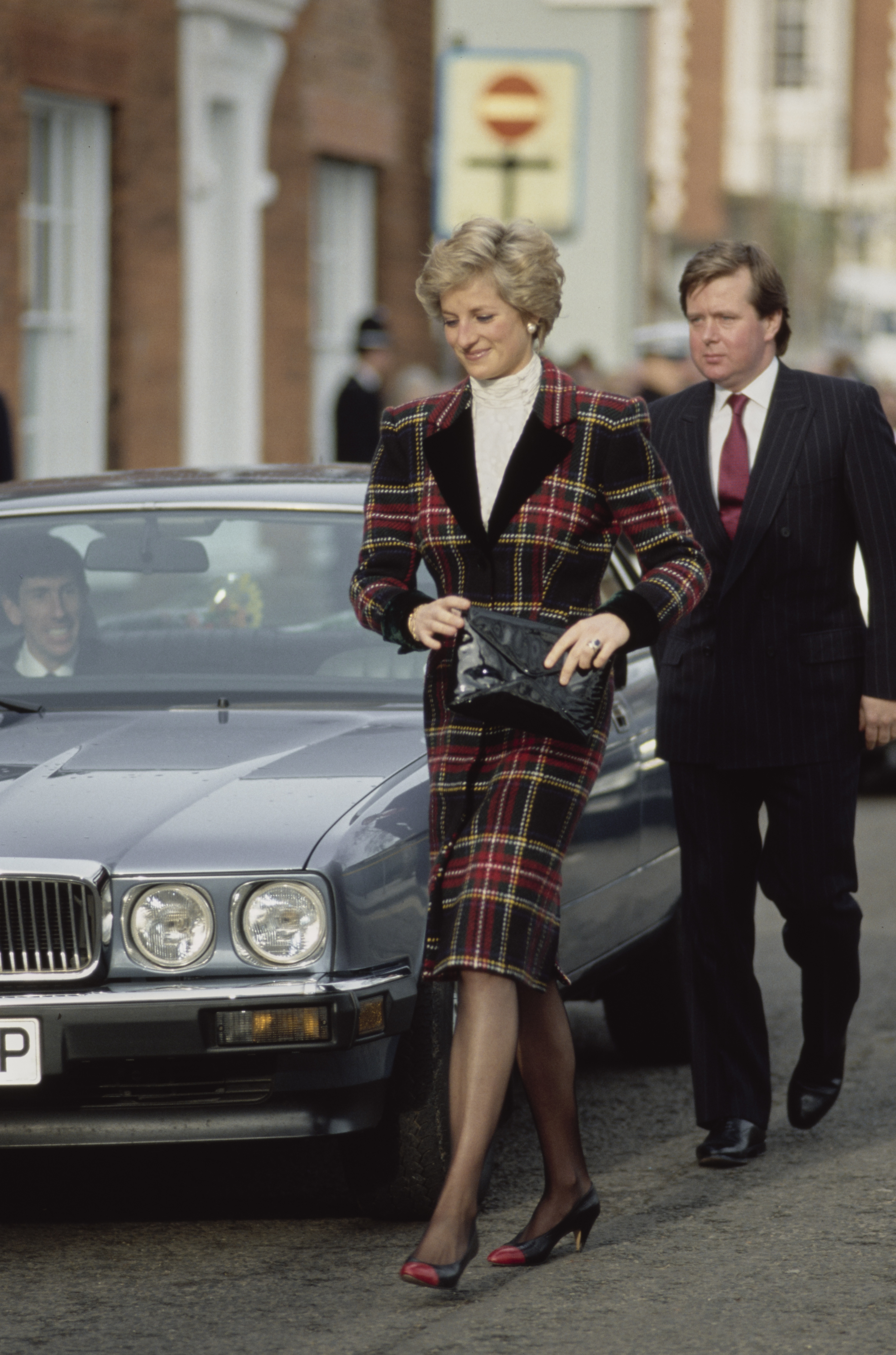 Princess Diana in a plaid suit walking in front of her bodyguard Ken Wharfe