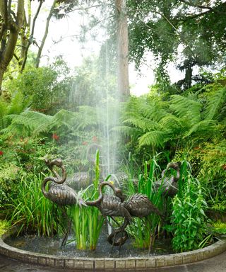pond with metal flamingoes and water jet