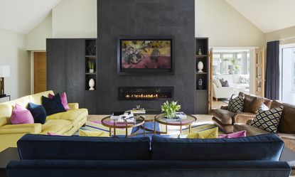 TV mounting ideas Yellow, grey and pink living room with leather sofa and TV mounted onto the wall 