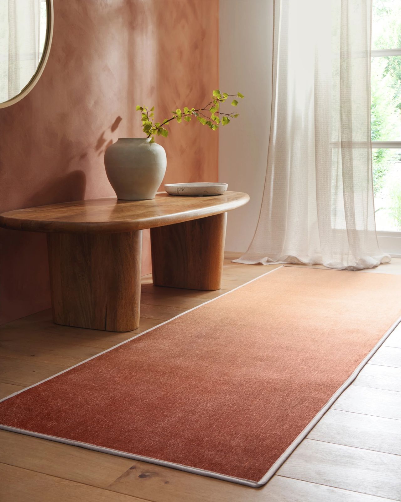 Hug Rug x Livingetc rug collaboration with coral ombre runner in hallway next to bench and potted plant with sheer curtains