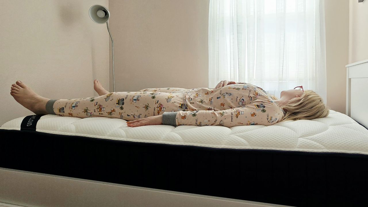 Mattress tester in cat pajamas rests on her back for the DreamCloud Classic Memory Foam Mattress review
