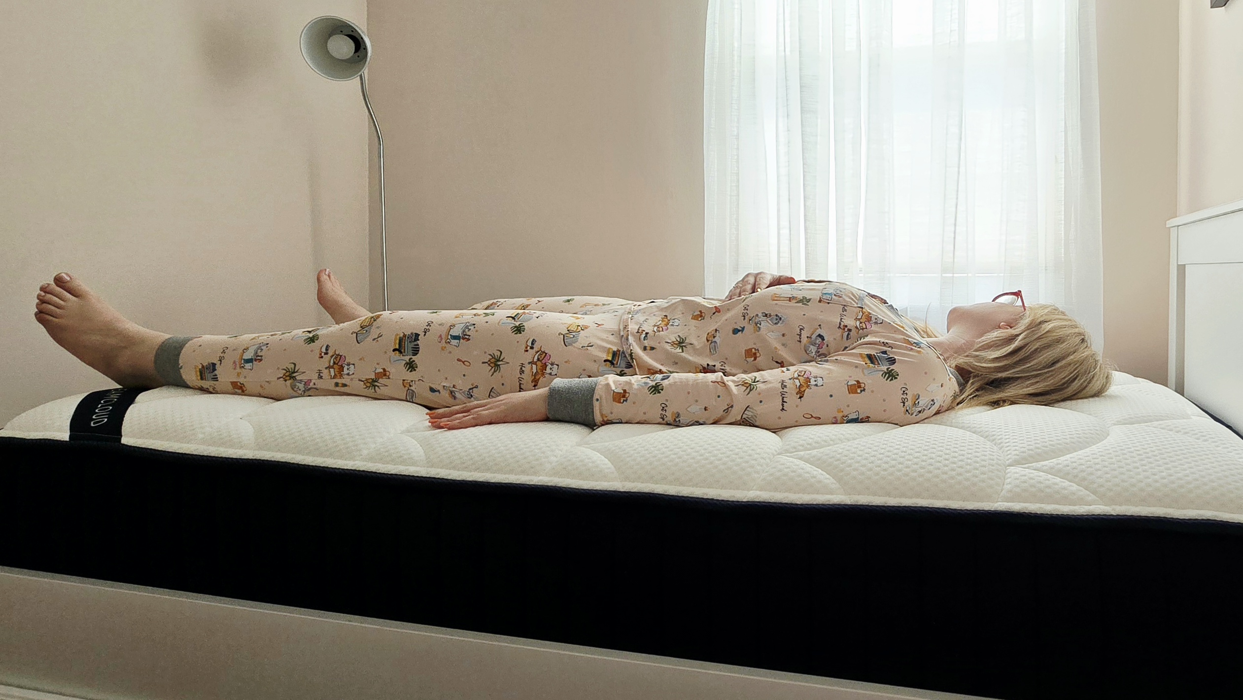 Mattress tester in cat pajamas rests on her back for the DreamCloud Classic Memory Foam Mattress review