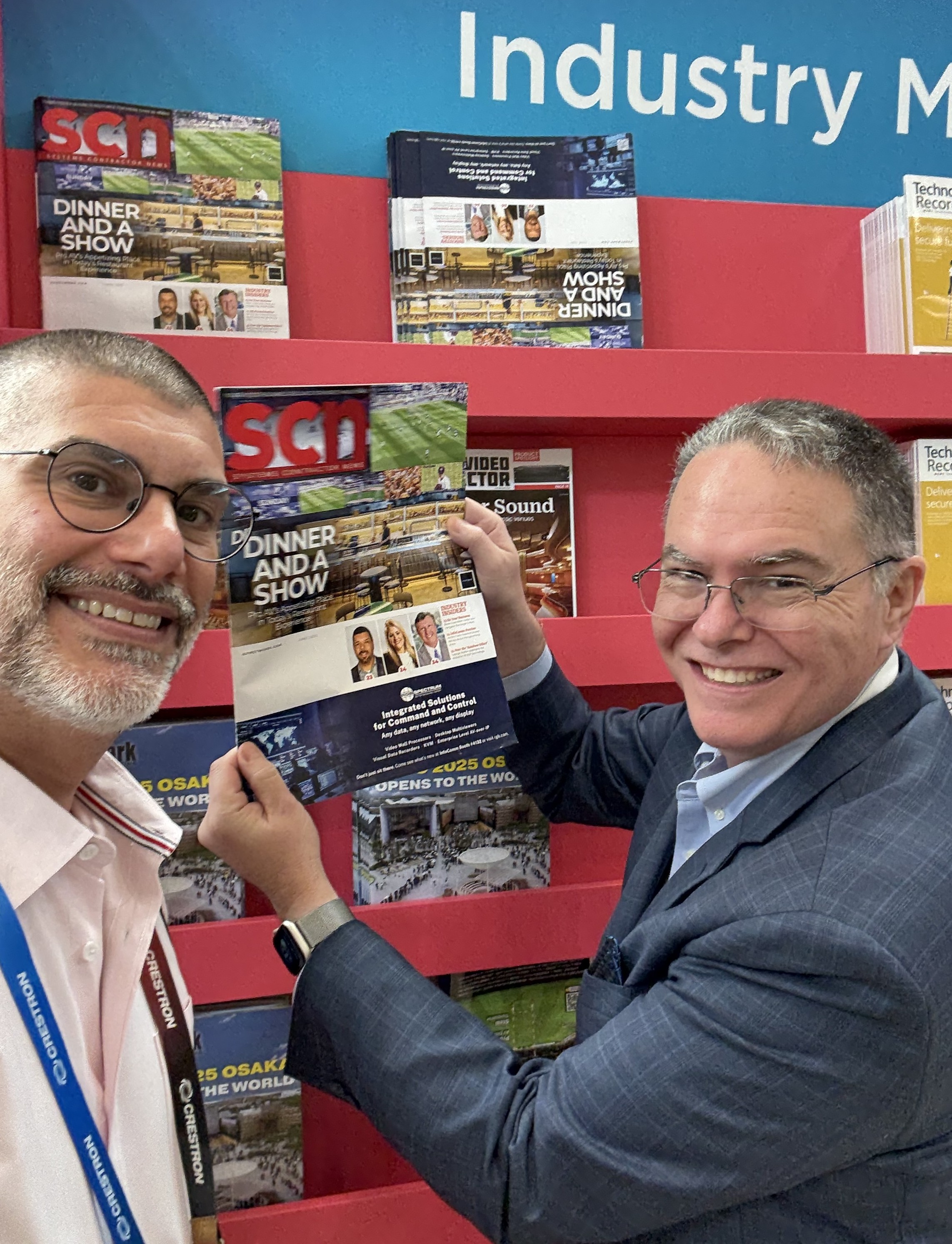 Wayne Cavadi and Mark J. Pescatore are all smiles, holding up their latest issue at InfoComm 2025.