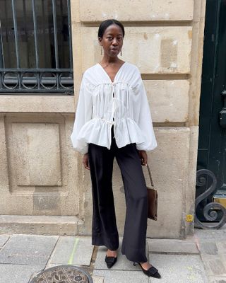 woman wearing a white blouse with black trousers and Manolo Blahnik mules