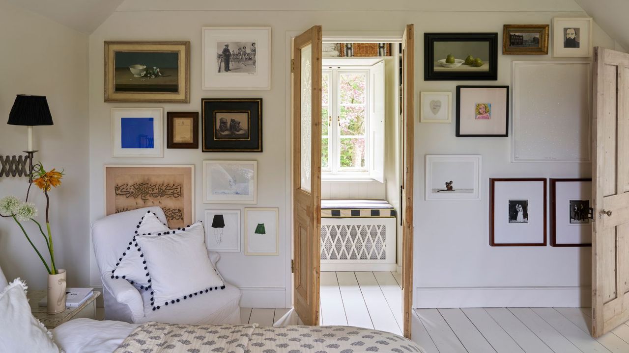 Bright bedroom with a gallery wall and bare wooden doors open to reveal a seated nook with window bench, cushion and white, crittal window