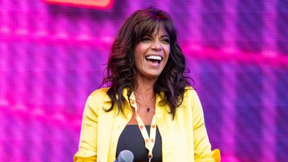 Jenny Powell on stage in a yellow shirt 