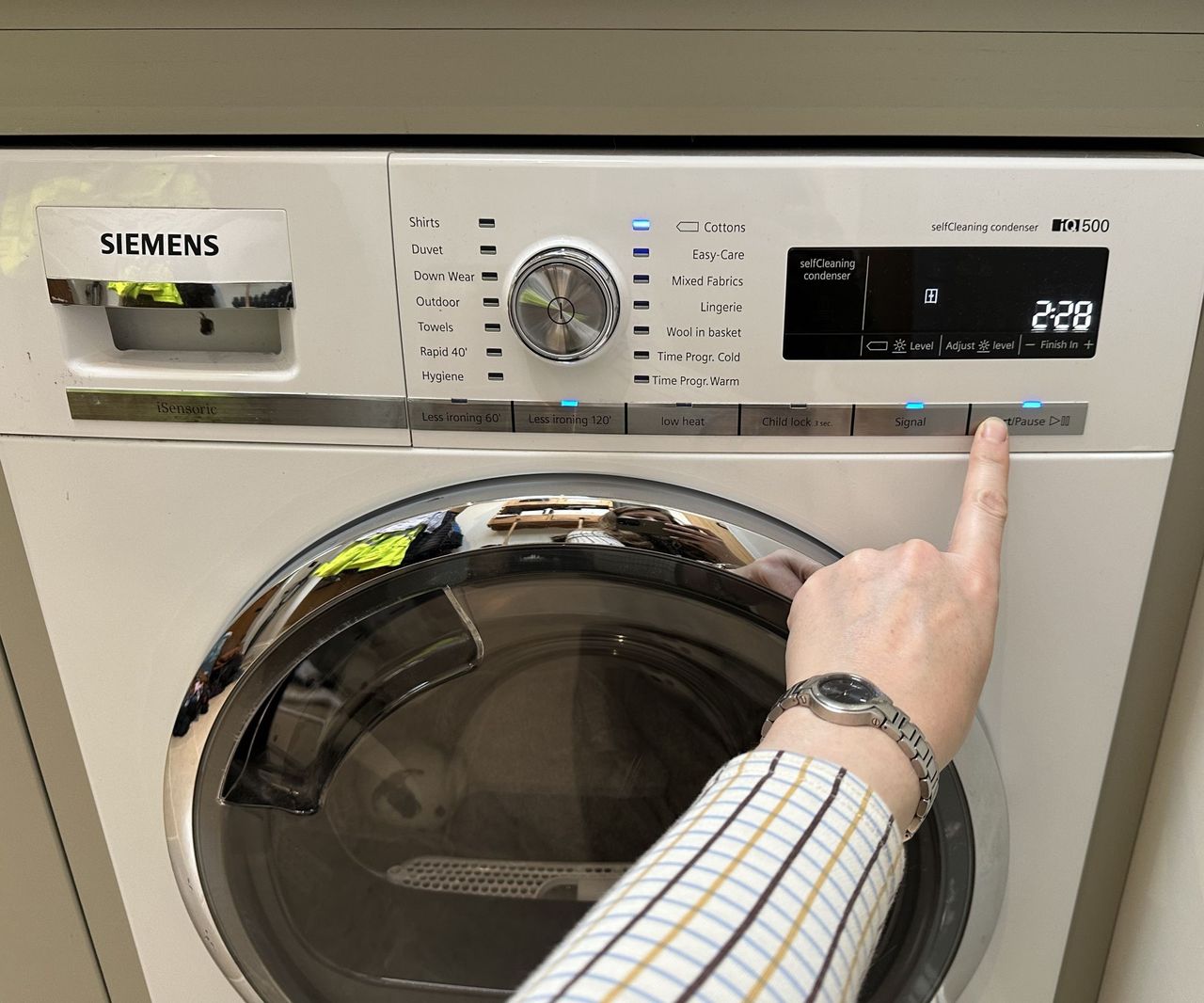 Pressing the dials of the Siemens heat pump tumble dryer to make it start or pause