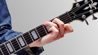 Close-up of hand playing chord on electric guitar neck