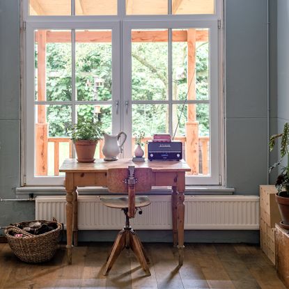 vintage desk and chair in front of a large window looking out on a verandah