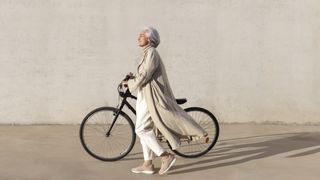 woman walking with bike beside cream wall