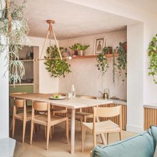 Dining room with plaster-effect walls and a wooden dining room table in the middle of it
