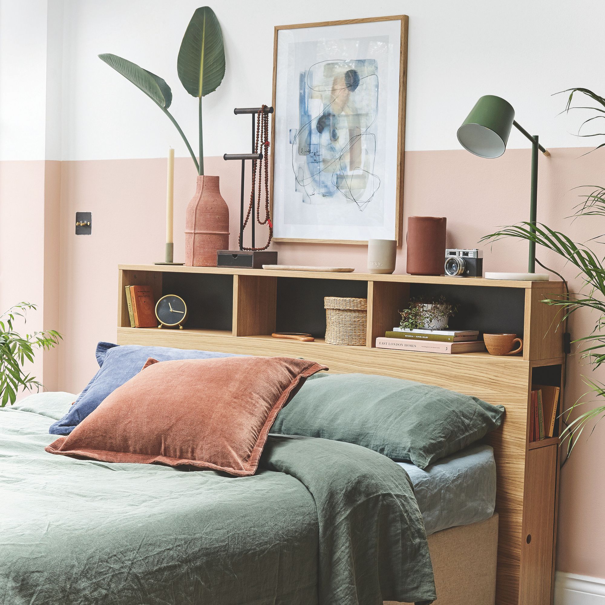 White and pink painted bedroom with storage headboard and green bedding on the bed