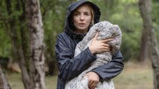 Jodie Comer in the film The End We Start From, holding a baby in the rain