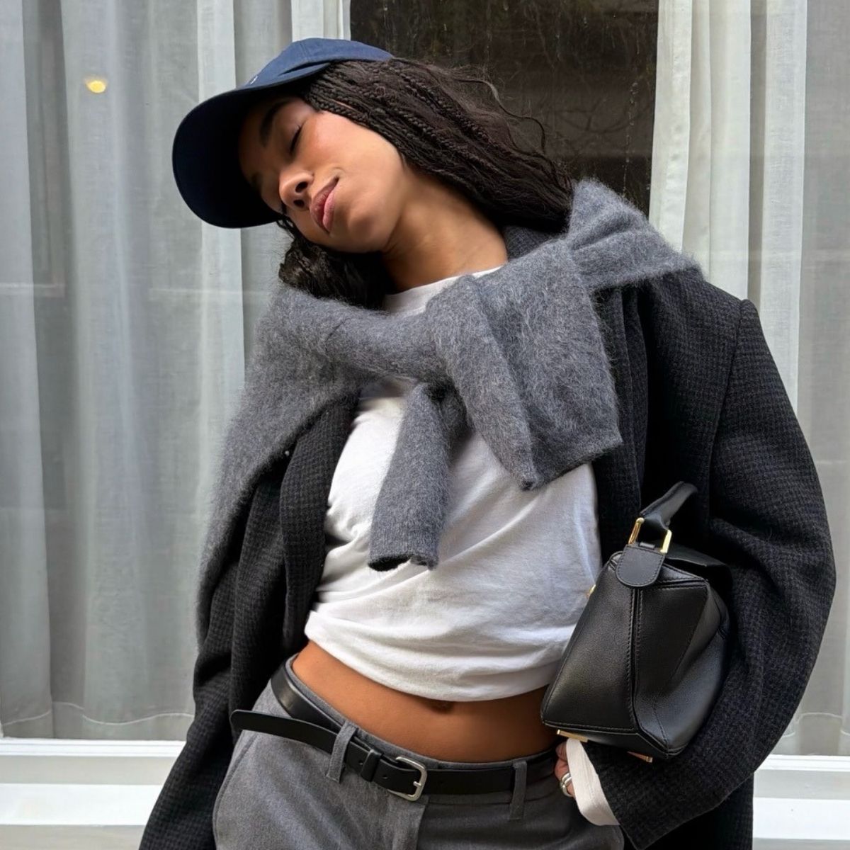 A woman in a grey blazer wearing a navy cap with her hair down