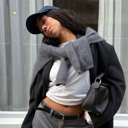 A woman in a grey blazer wearing a navy cap with her hair down