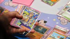 A competitor holds a deck showing an Arven card as they play the Pok&eacute;mon Trading Card Game 