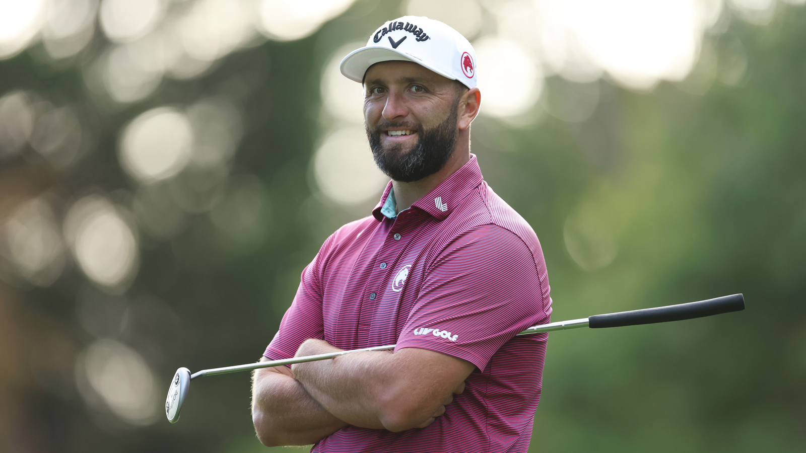 Jon Rahm smiles while waiting to hit a putt
