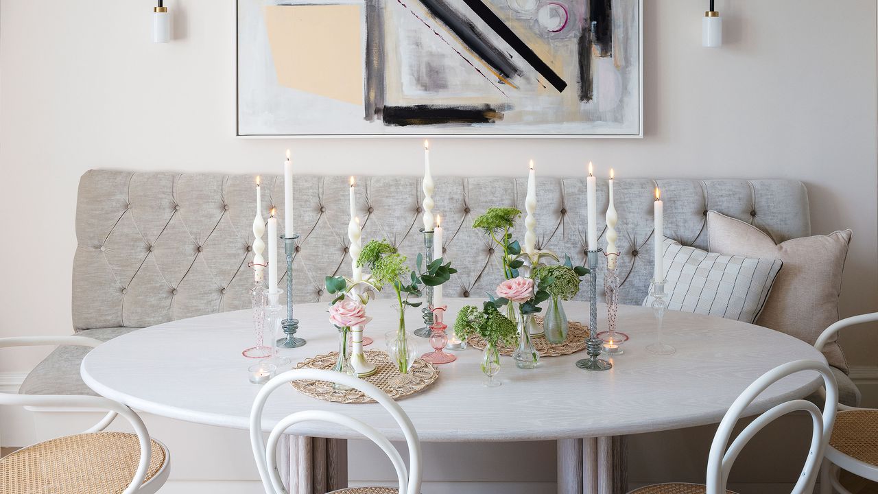 white kitchen dining area with white chairs, white circular table and light gray banquette