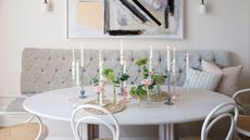 white kitchen dining area with white chairs, white circular table and light gray banquette