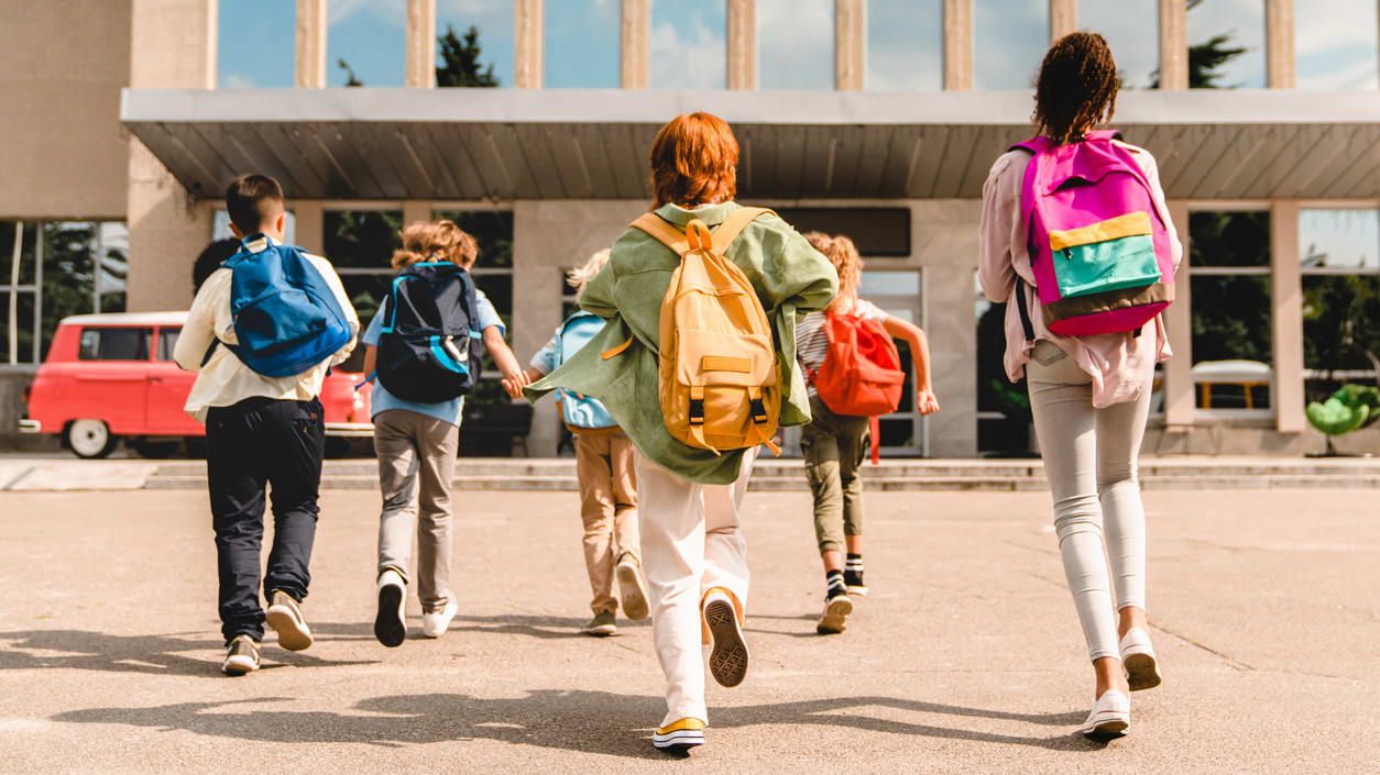 Kids run to their school.