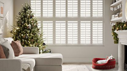 A christmas tree in the corner of a white living room