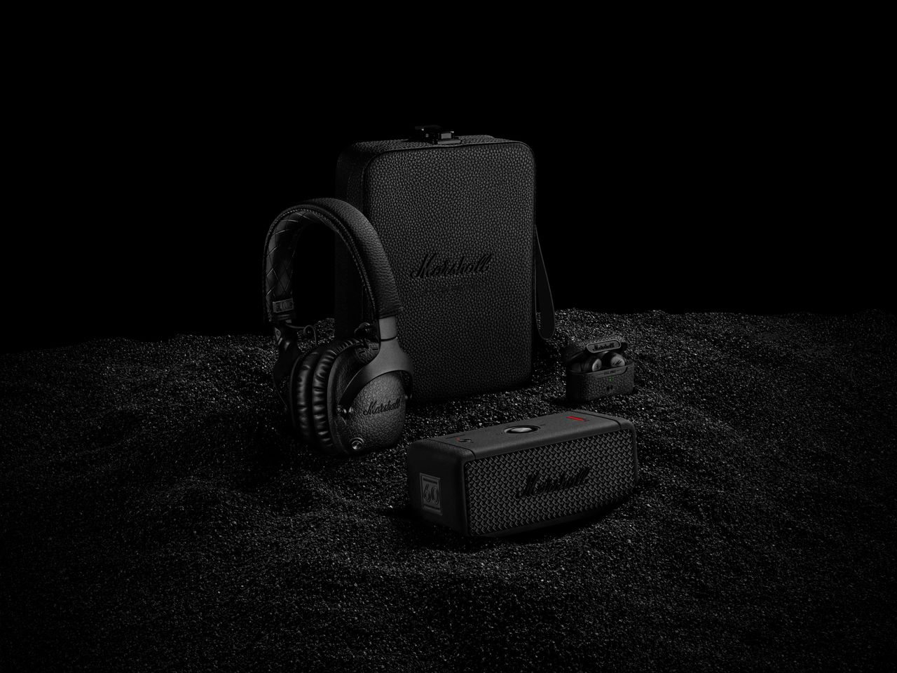 Three limited edition black diamond coloured headphones, earphones and speakers on a black background