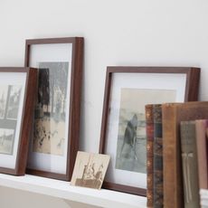 white wall with shelf and photo frames