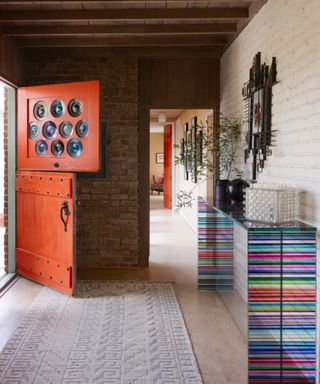 Colorful entryway with orange front door and striped side table