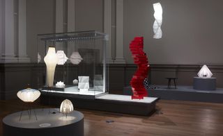 A display of various lamp designs of differing sizes, plus a craft design with red plastic squares stacked in a spiral.