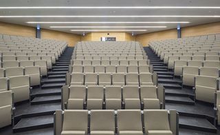 View of the auditorium in the Grotius Building, Nijmegen, rows of beige seating, black steps, yellow walls, white ceiling with strobe lighting