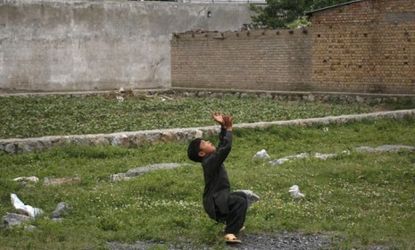 A boy plays with a ball in front of Osama bin Laden's Pakistan compound: Neighborhood kids would not get their balls returned if they were lost in the terrorist's yard.