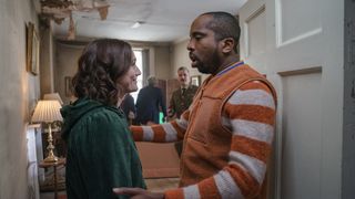 Charlotte Ritchie in a green top as Alison faces Kiell Smith-Bynoe in an orange and white top as Mike inside Button House in Ghosts.