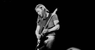 A B/W image of David Gilmour performs with Pink Floyd in 1977, playing his Black Strat